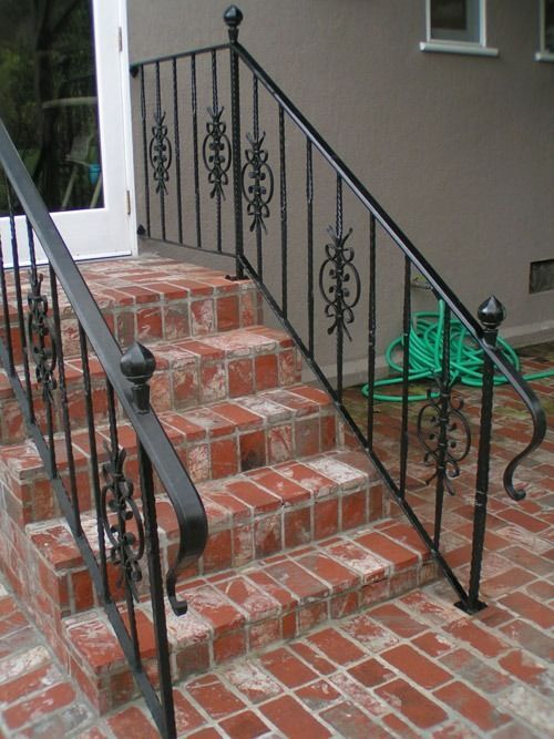 Brick front steps with black wrought-iron railings beside a house entrance