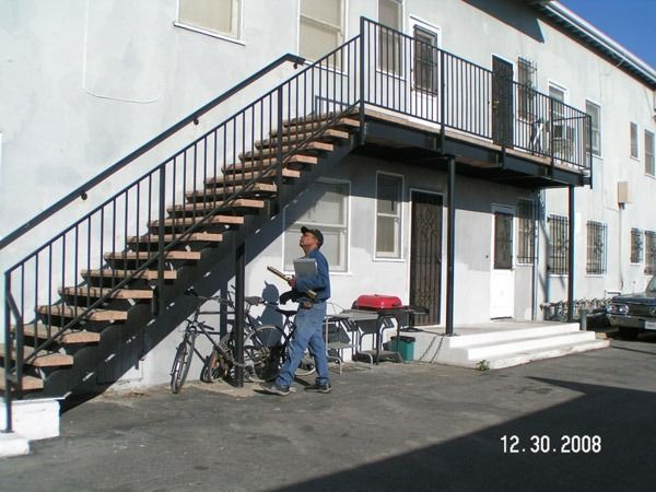 Person standing by bicycles under outdoor apartment staircase with metal railing