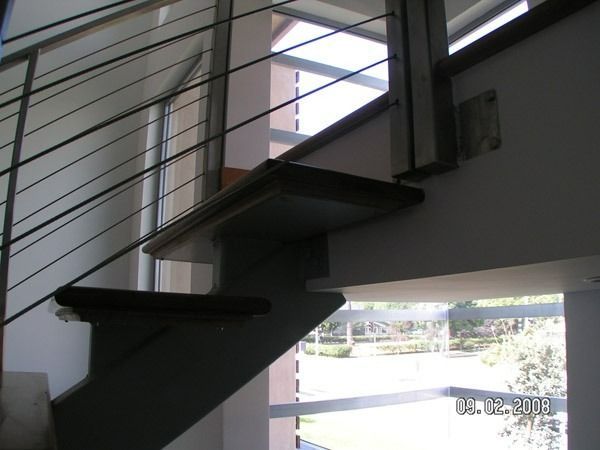 Modern indoor staircase with metal railing and window light.