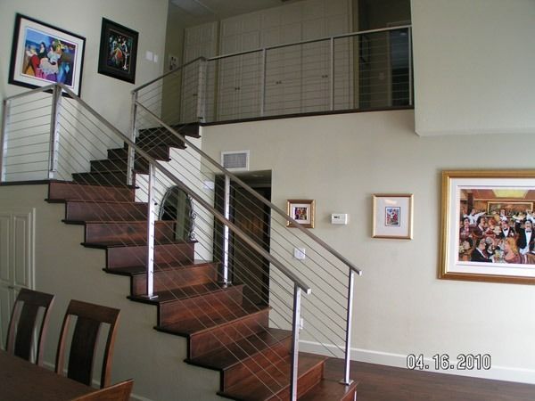 Indoor staircase with dark wood steps, metal railing, and framed artwork on white walls