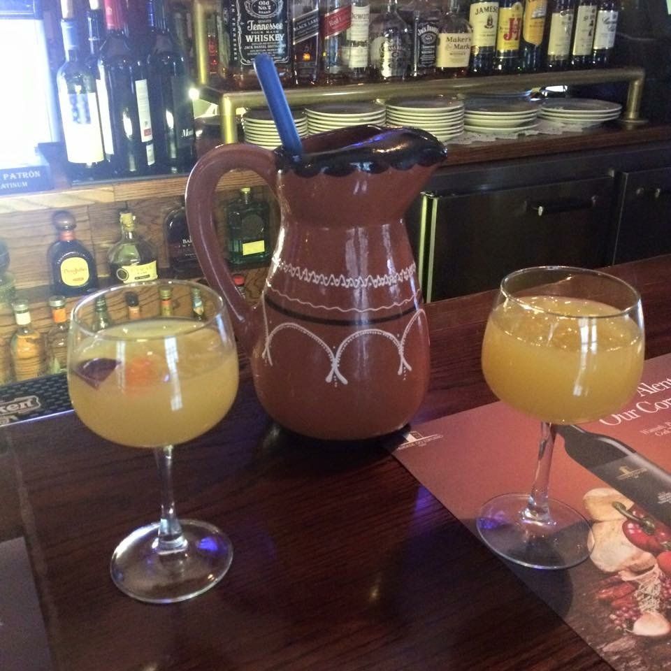 A pitcher and two glasses of orange juice on a bar