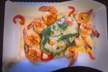 A white plate topped with shrimp and rice on a table.