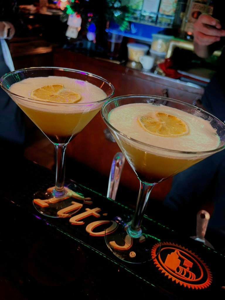 Two martini glasses are sitting on a bar.