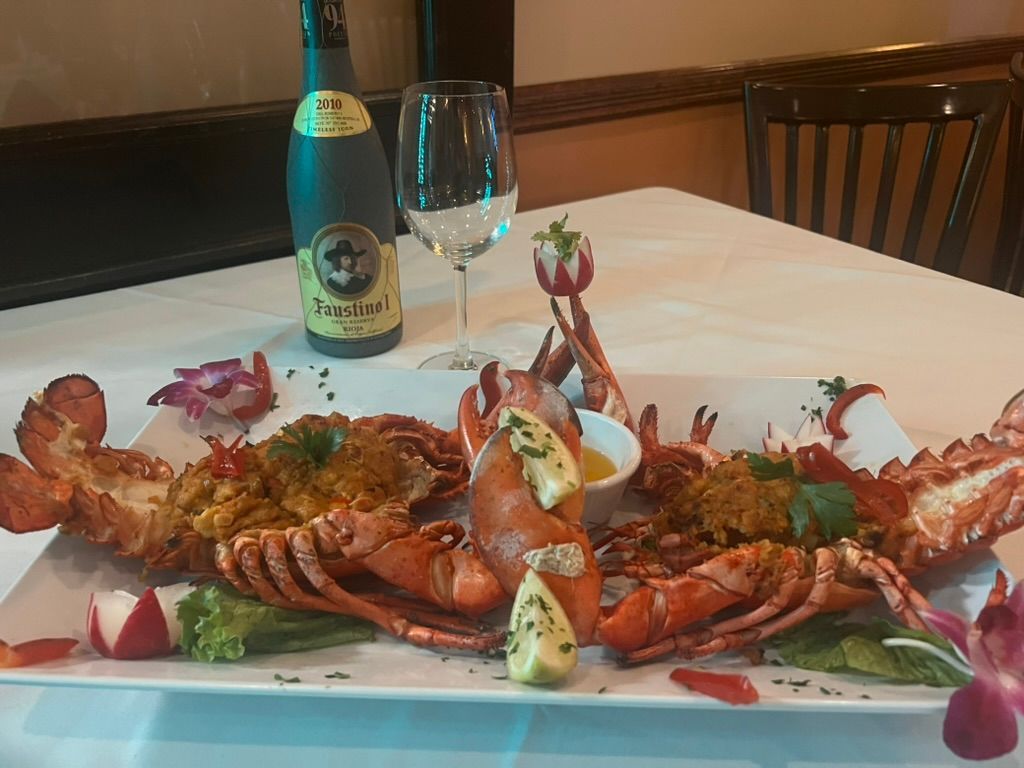 A plate of lobsters and a bottle of wine on a table.