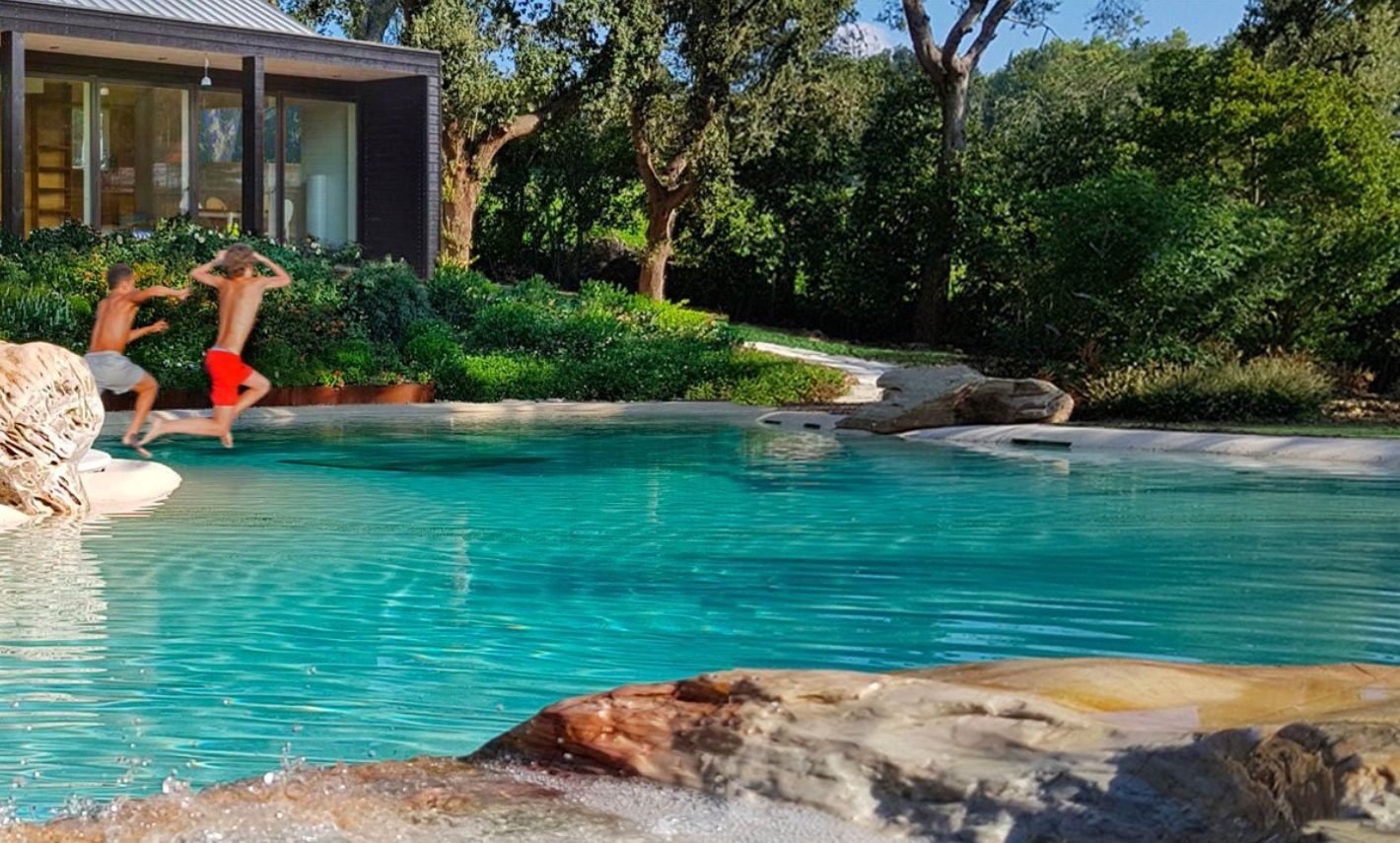 Two men are jumping into a swimming pool in front of a house.