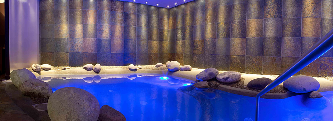 A large swimming pool is surrounded by a patio and a wooden fence.