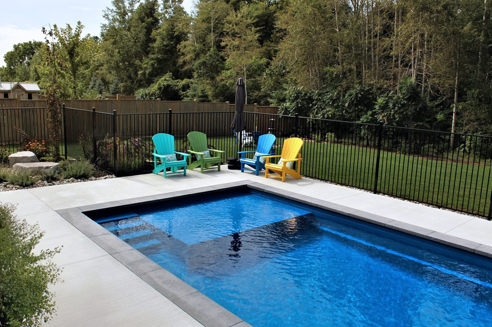 A large swimming pool surrounded by chairs and a fence.