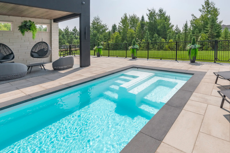 There is a large swimming pool in the backyard of a house.
