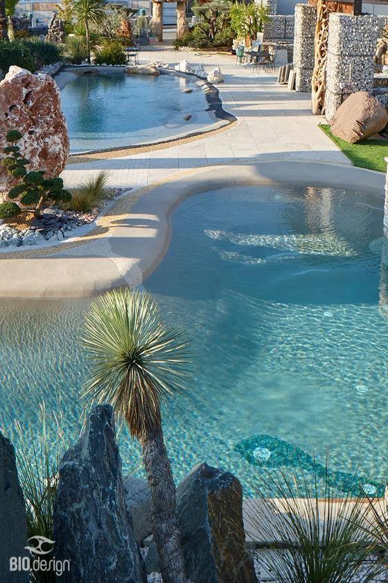 A large swimming pool surrounded by rocks and plants.
