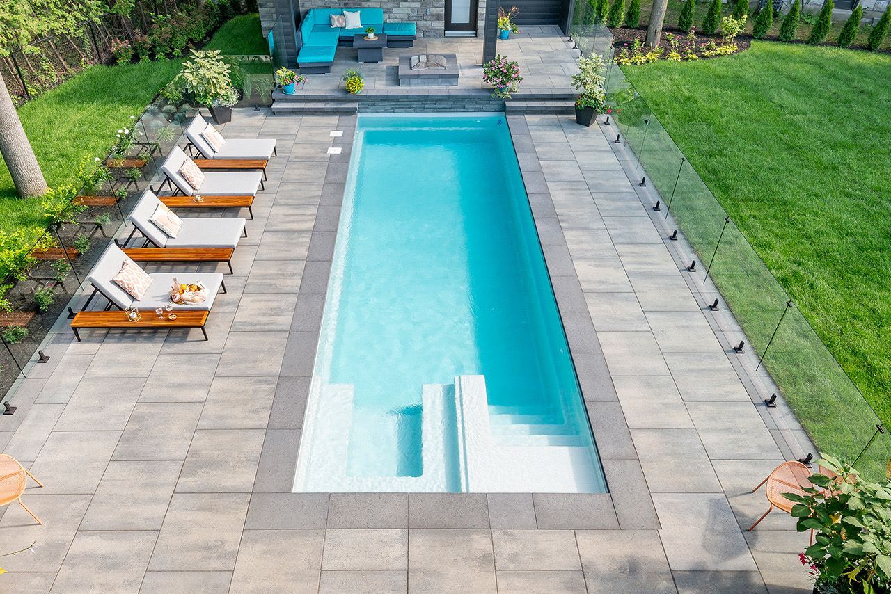 An aerial view of a large swimming pool in a backyard surrounded by chairs.