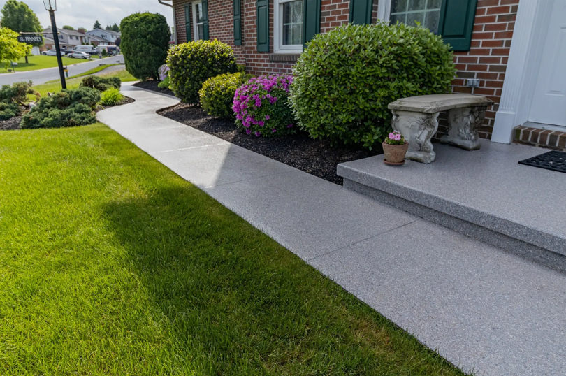A brick house with a concrete walkway leading to the front door.