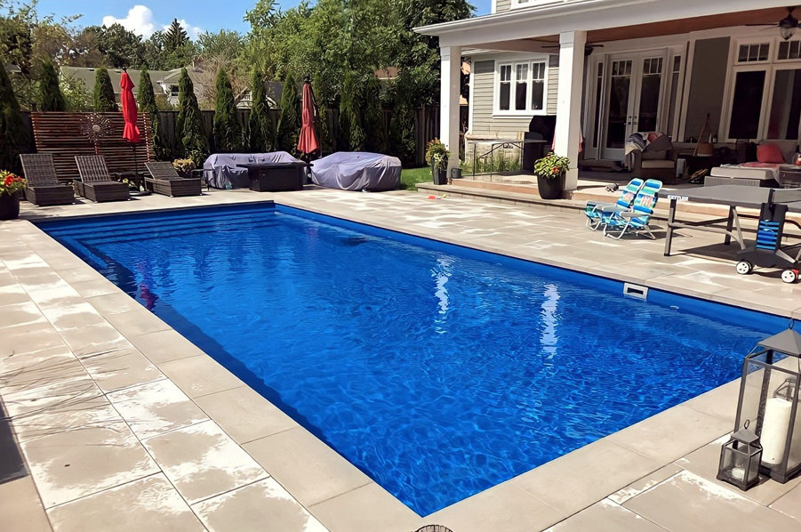 A large blue swimming pool is in the backyard of a house.