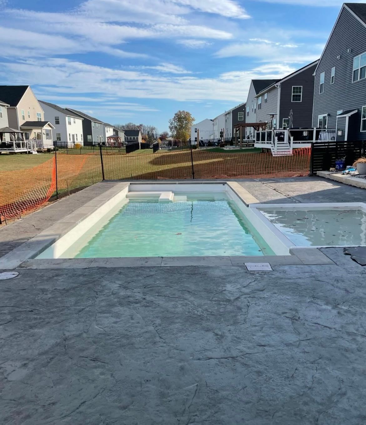 A swimming pool is surrounded by houses in a residential area