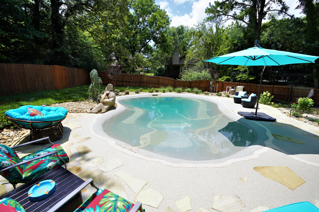 A large swimming pool surrounded by chairs and umbrellas in a backyard.