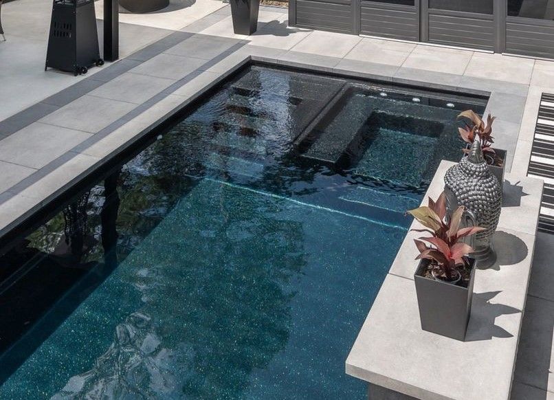 A large swimming pool is surrounded by planters and a patio.