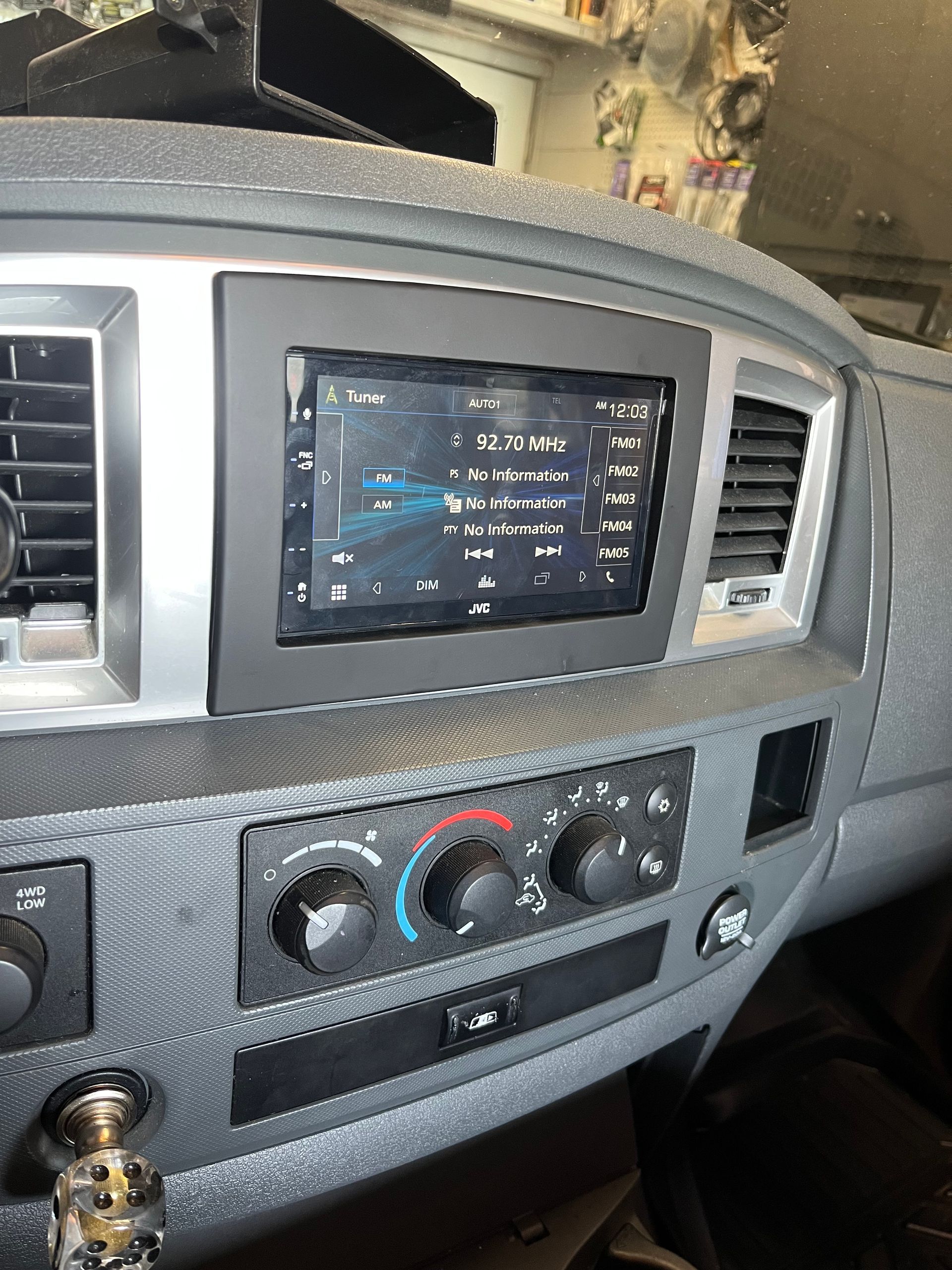 Car dashboard with central touchscreen, air vents, and climate controls in a gray interior.