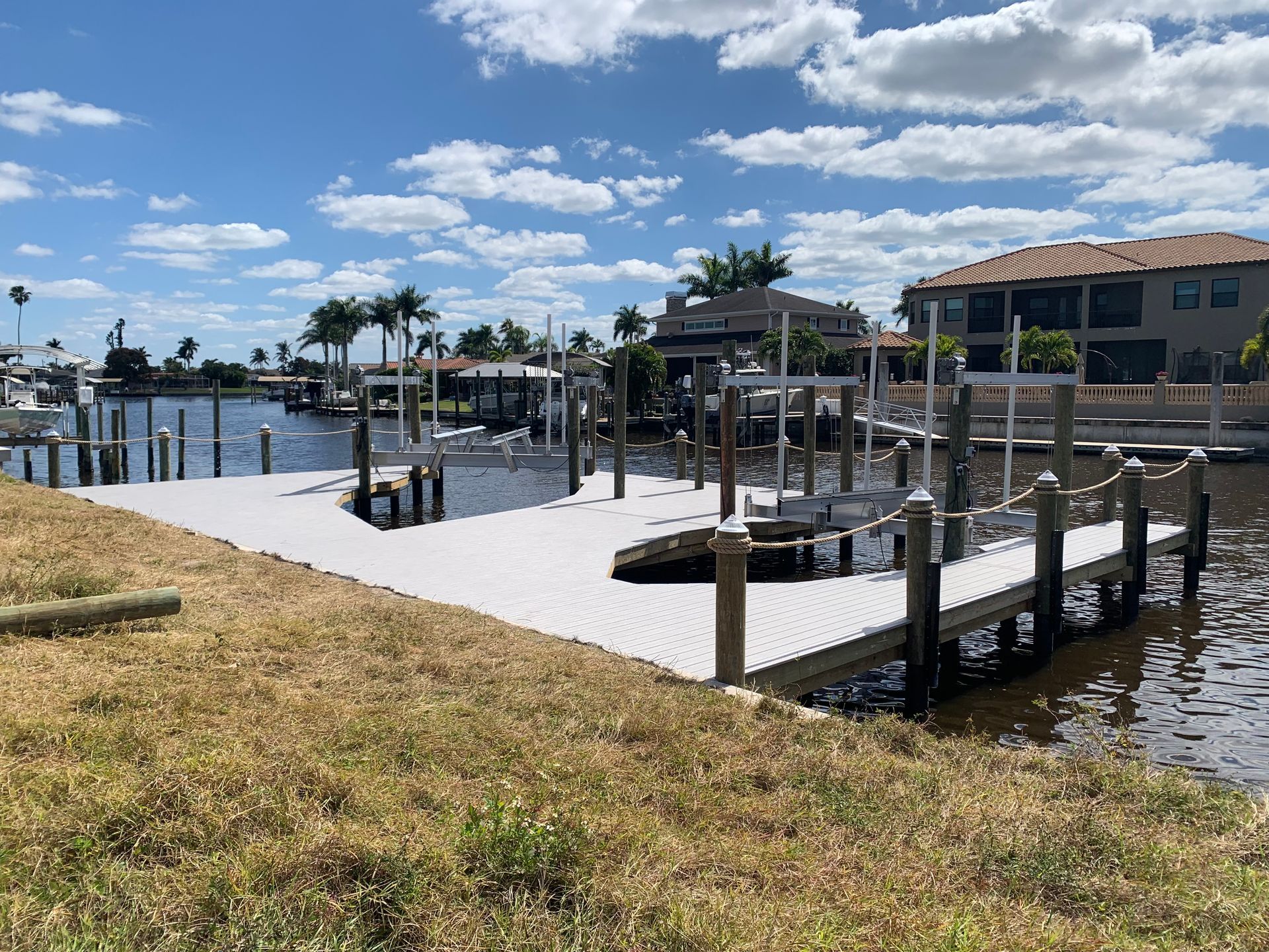 A dock in the middle of a body of water with a house in the background
