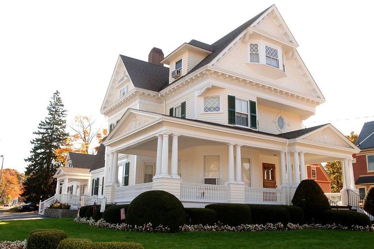 White Victorian house with porch, columns, and a green lawn.