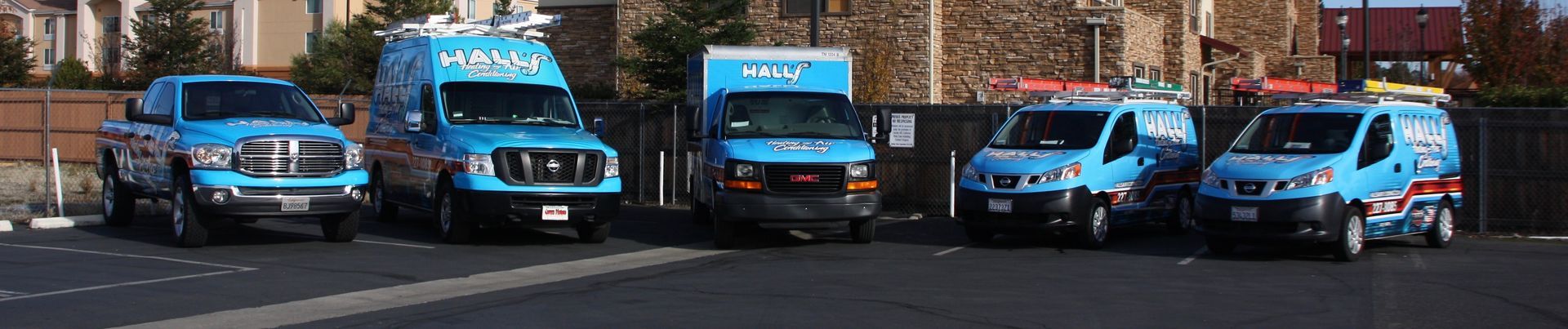 A row of blue vans are parked on the side of the road