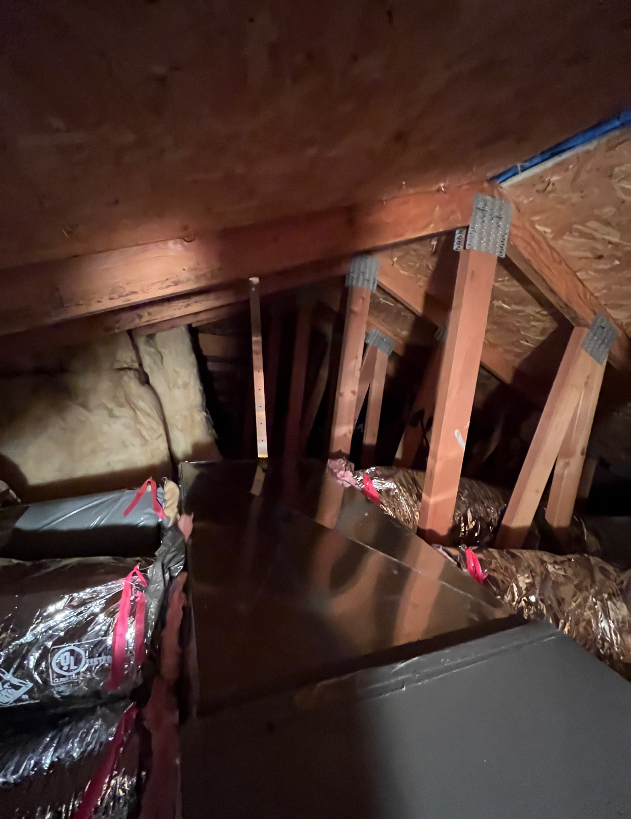 A dark attic with a lot of ducts and wooden beams