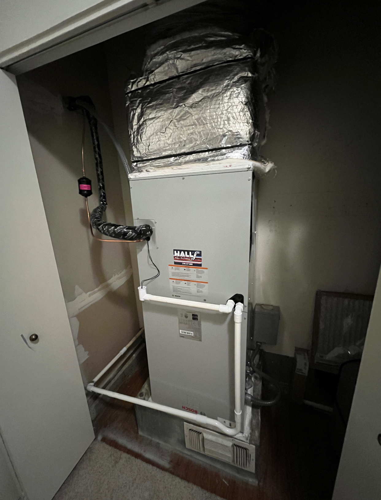 A large air conditioner is sitting inside of a closet