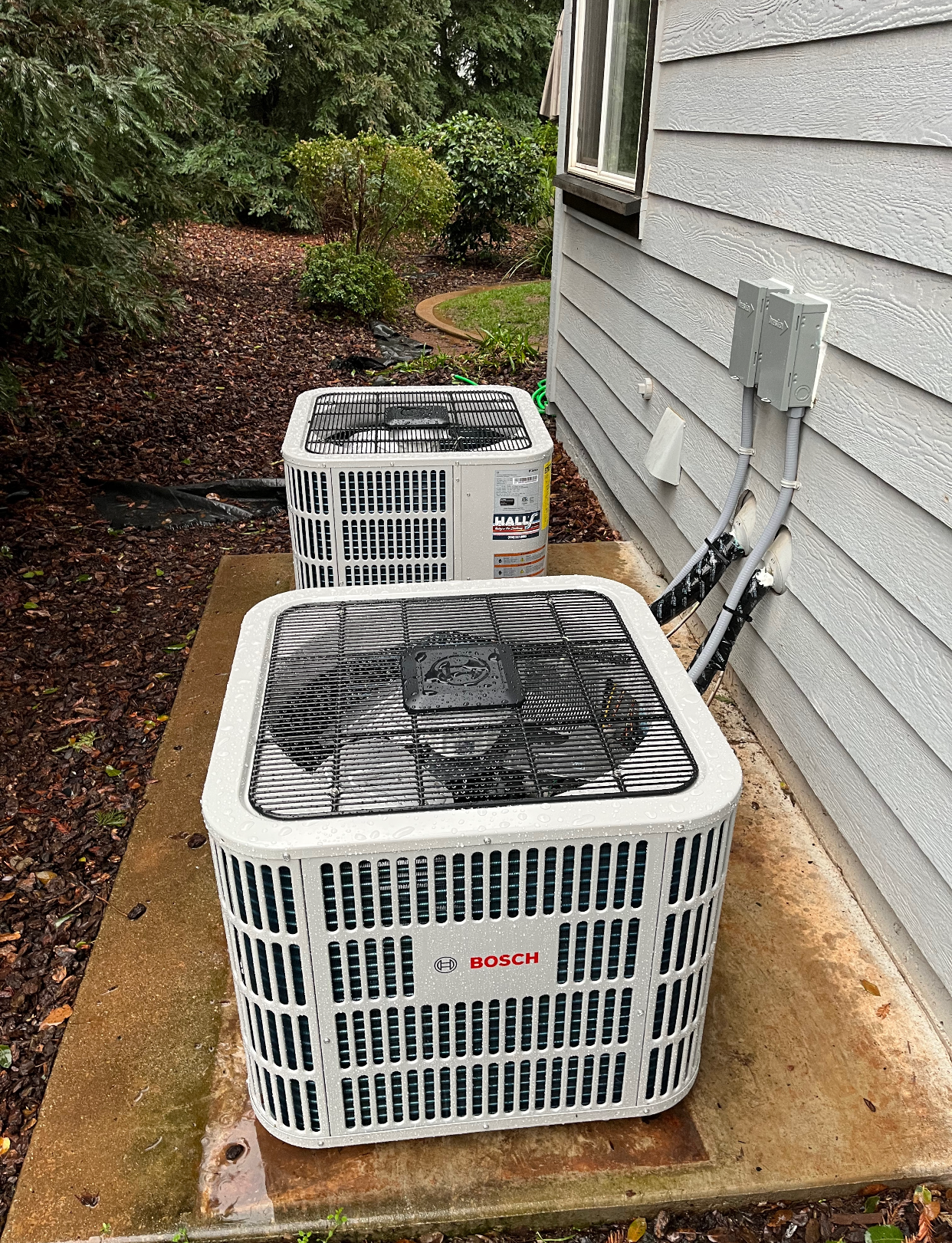 Two air conditioners are sitting on the side of a house