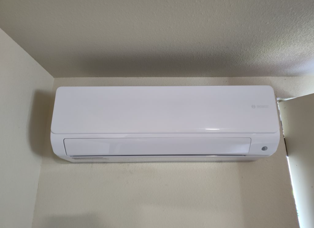 A white air conditioner is hanging on a wall in a room