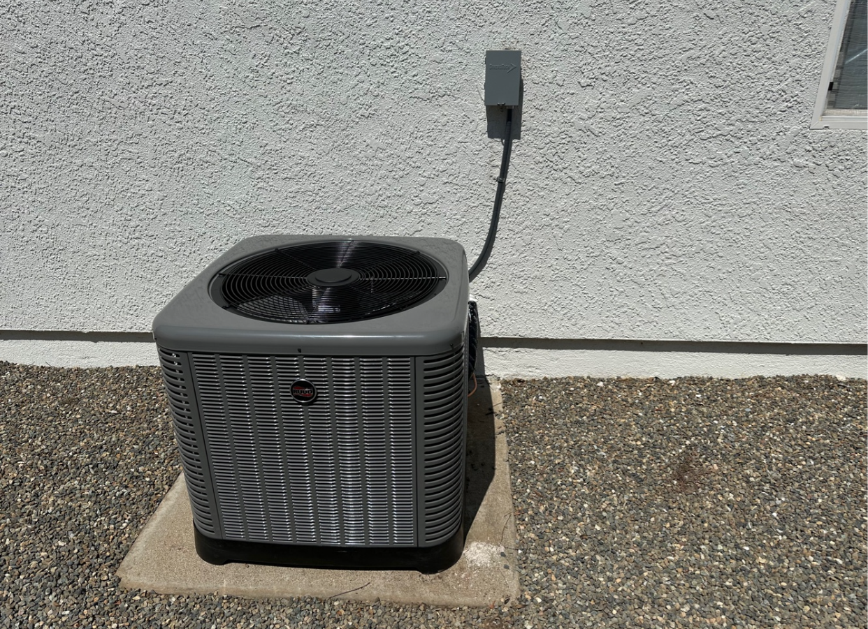 An air conditioner is sitting on the ground next to a wall