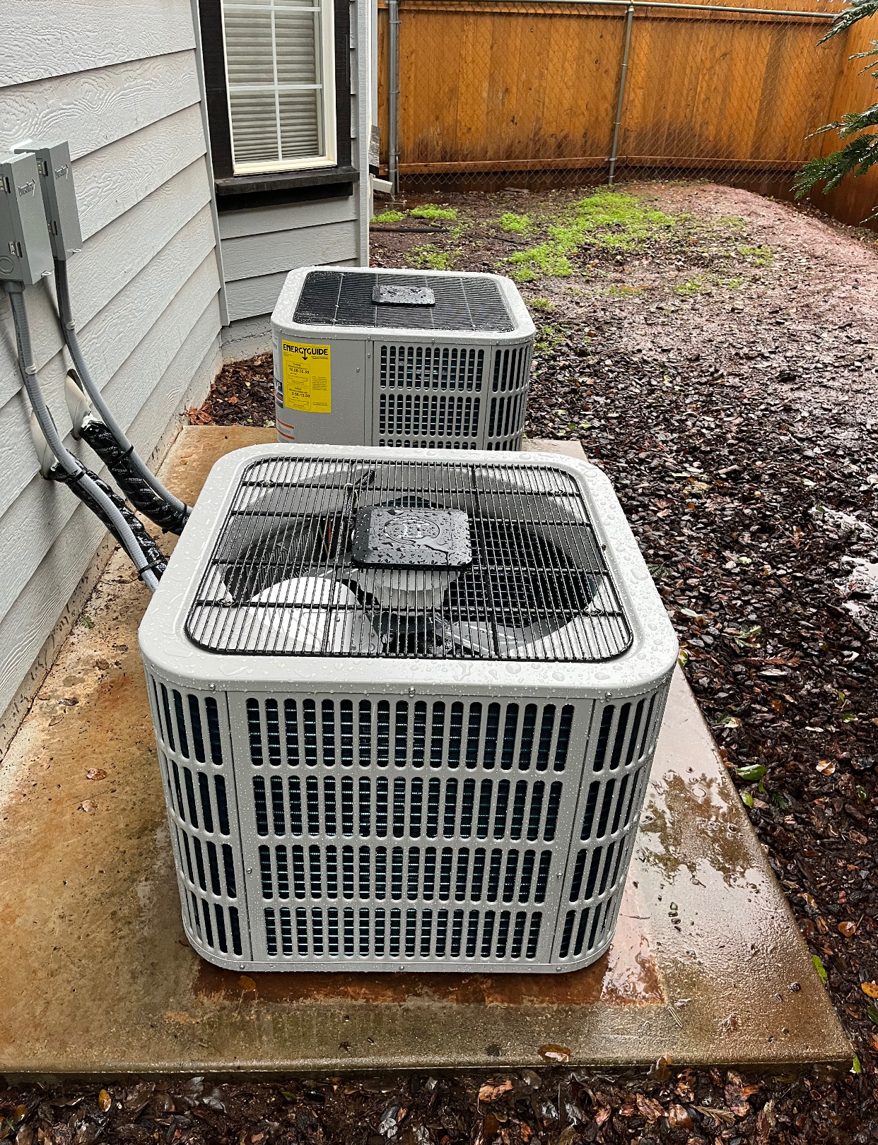 Two air conditioners are sitting on the side of a house