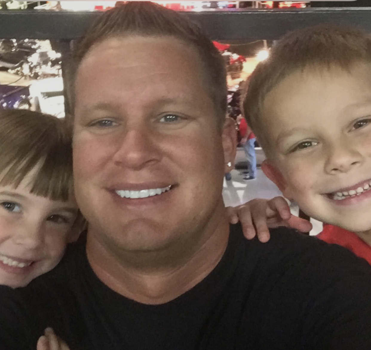 A man is posing for a picture with two young boys