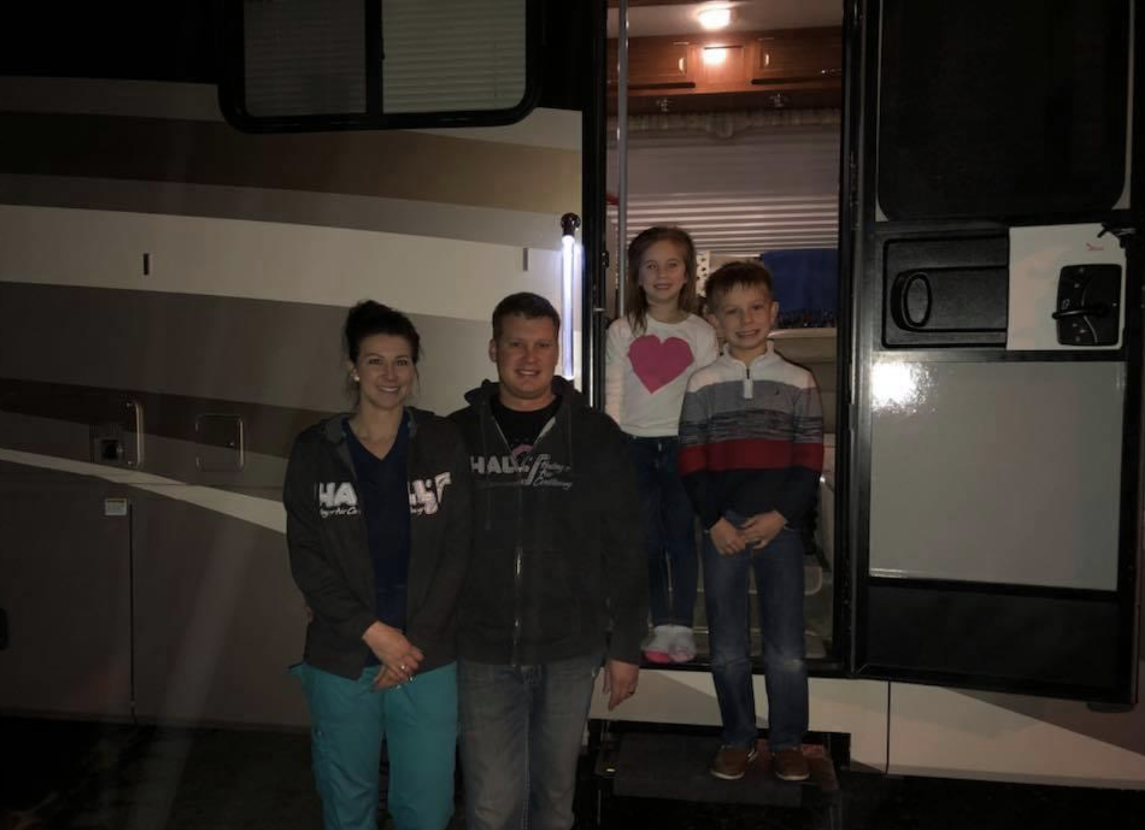A family is standing in front of a rv at night