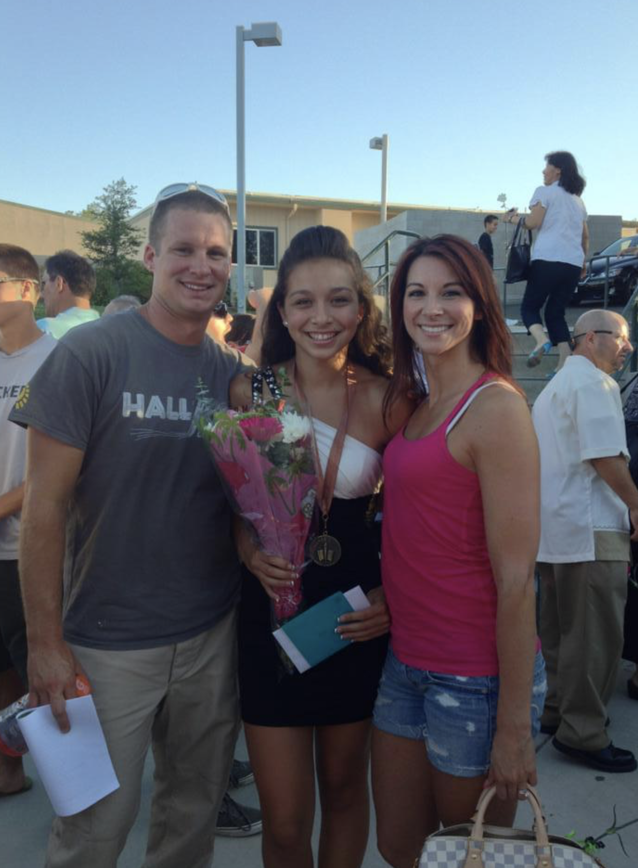 A man in a hall shirt poses with two women