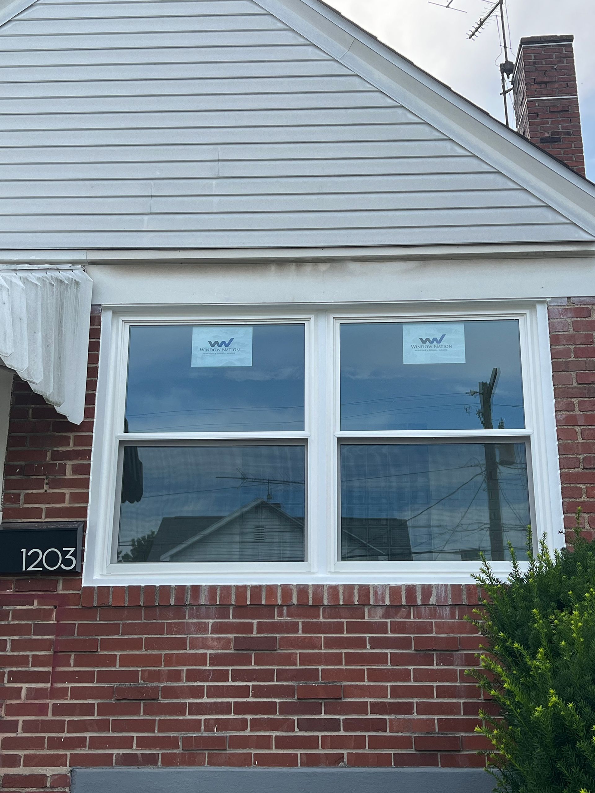 Brick house exterior with a new white double-hung window. Address 