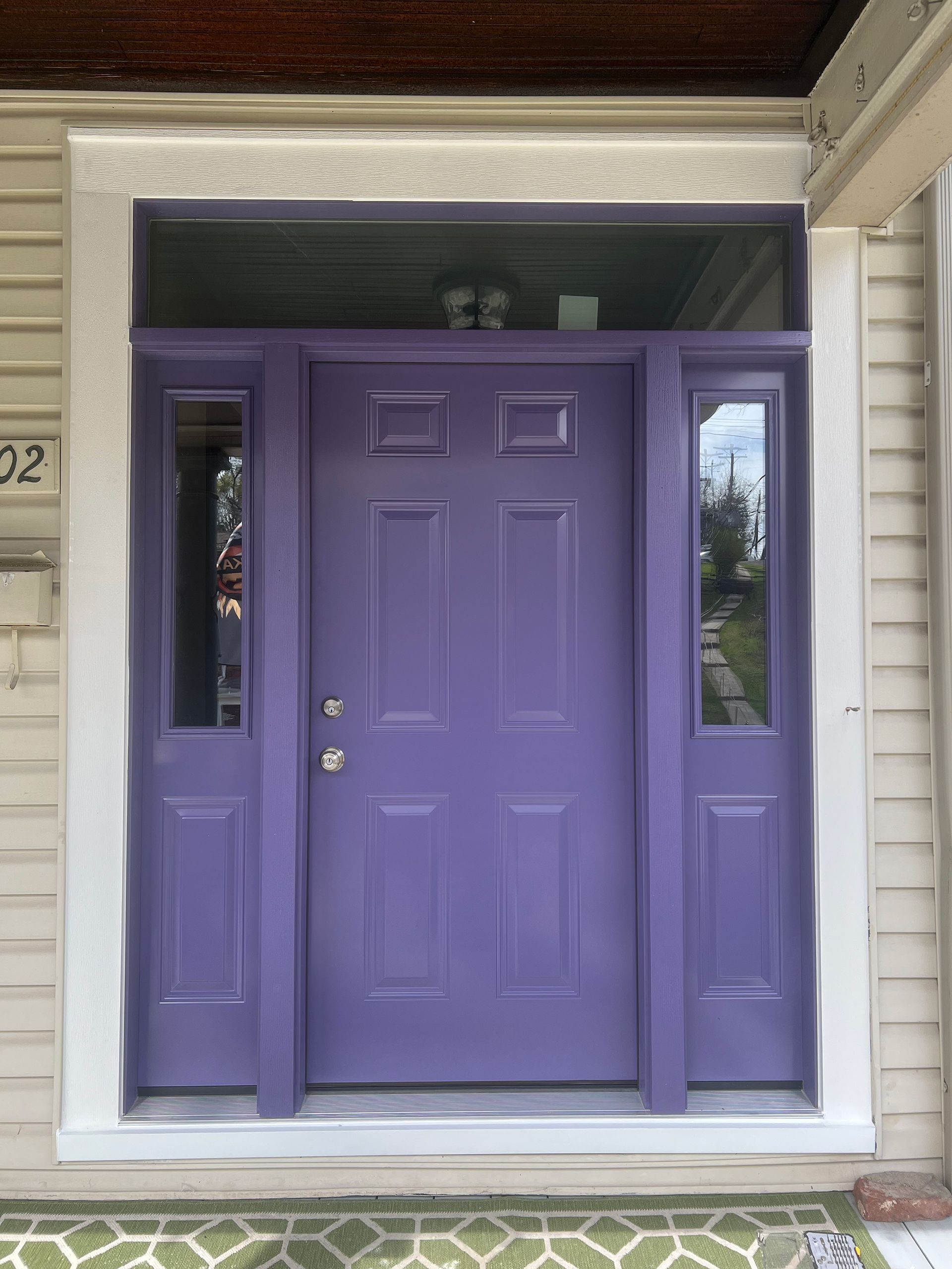 Purple front door with sidelights, white trim, on a beige house exterior.