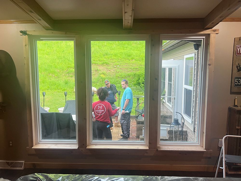 Three windows frame view of people outdoors. Interior with wood trim.