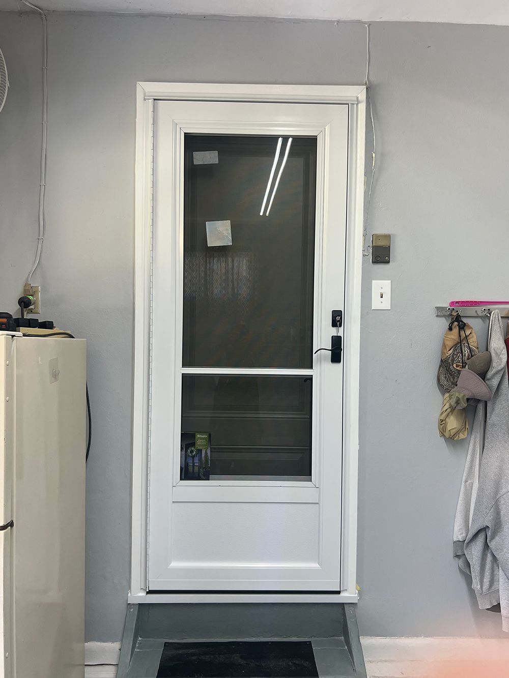 White screen door on a grey wall with a small step.