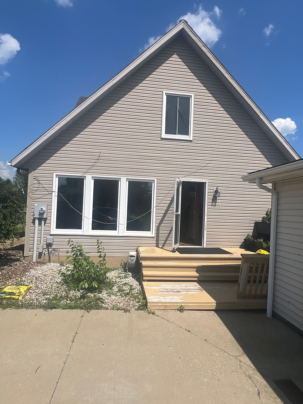 House exterior with gray siding, white-framed windows, and wooden deck steps.