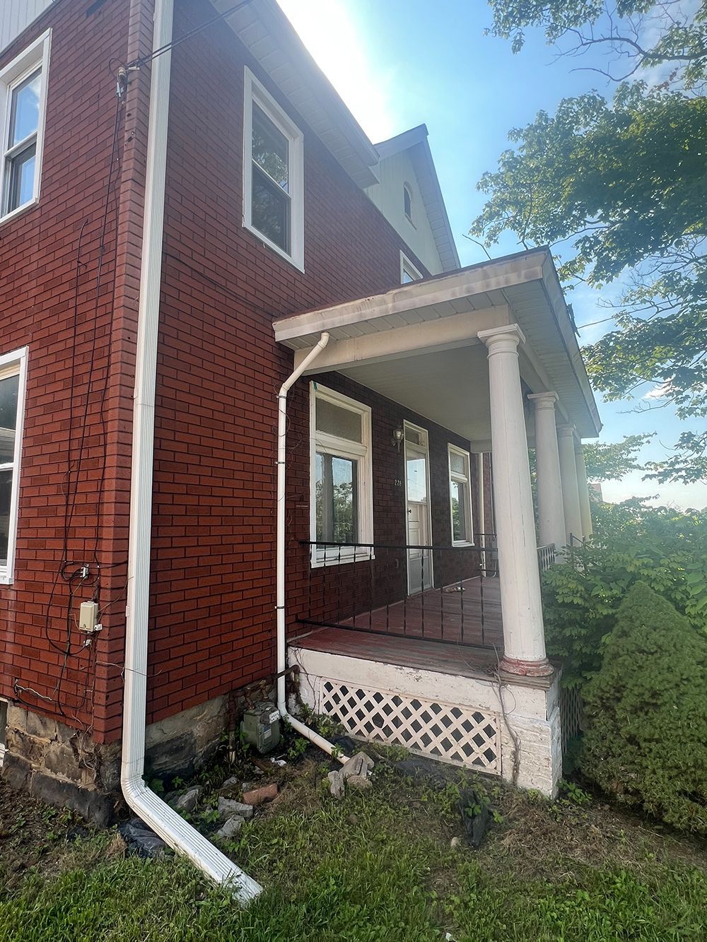 Red brick house with a white porch, columns, and gutters.