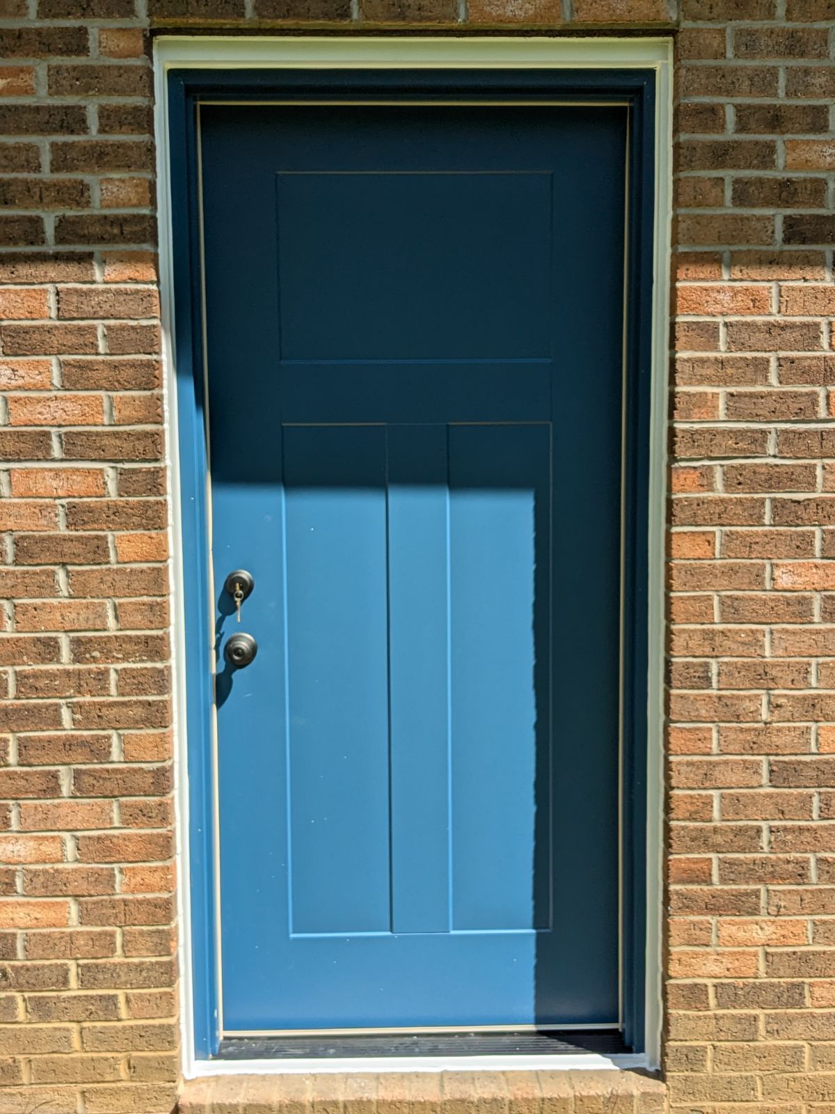 Blue front door set in brick wall.