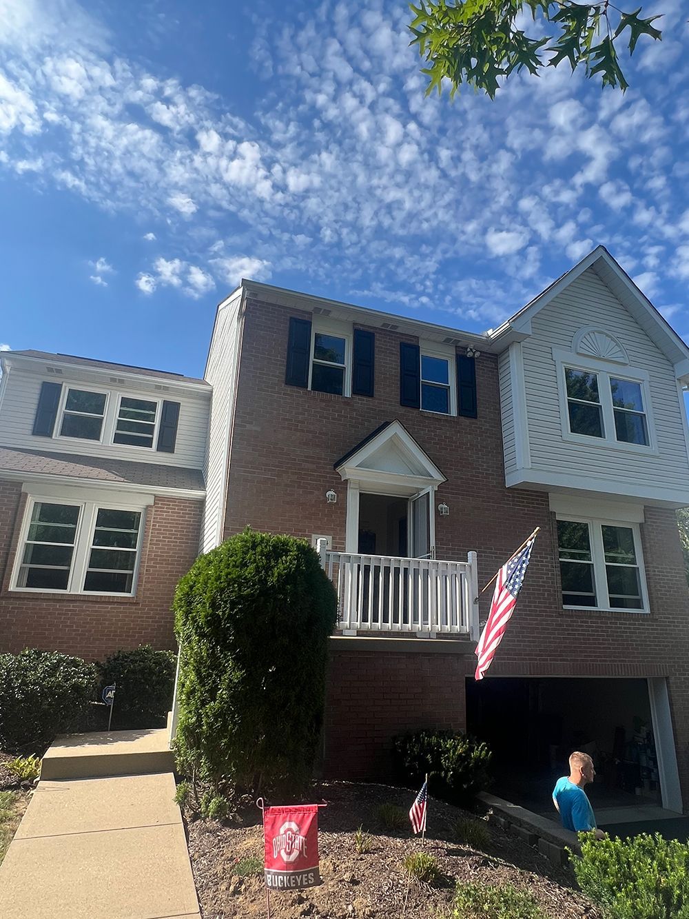 Brick townhome with American flag; blue sky.