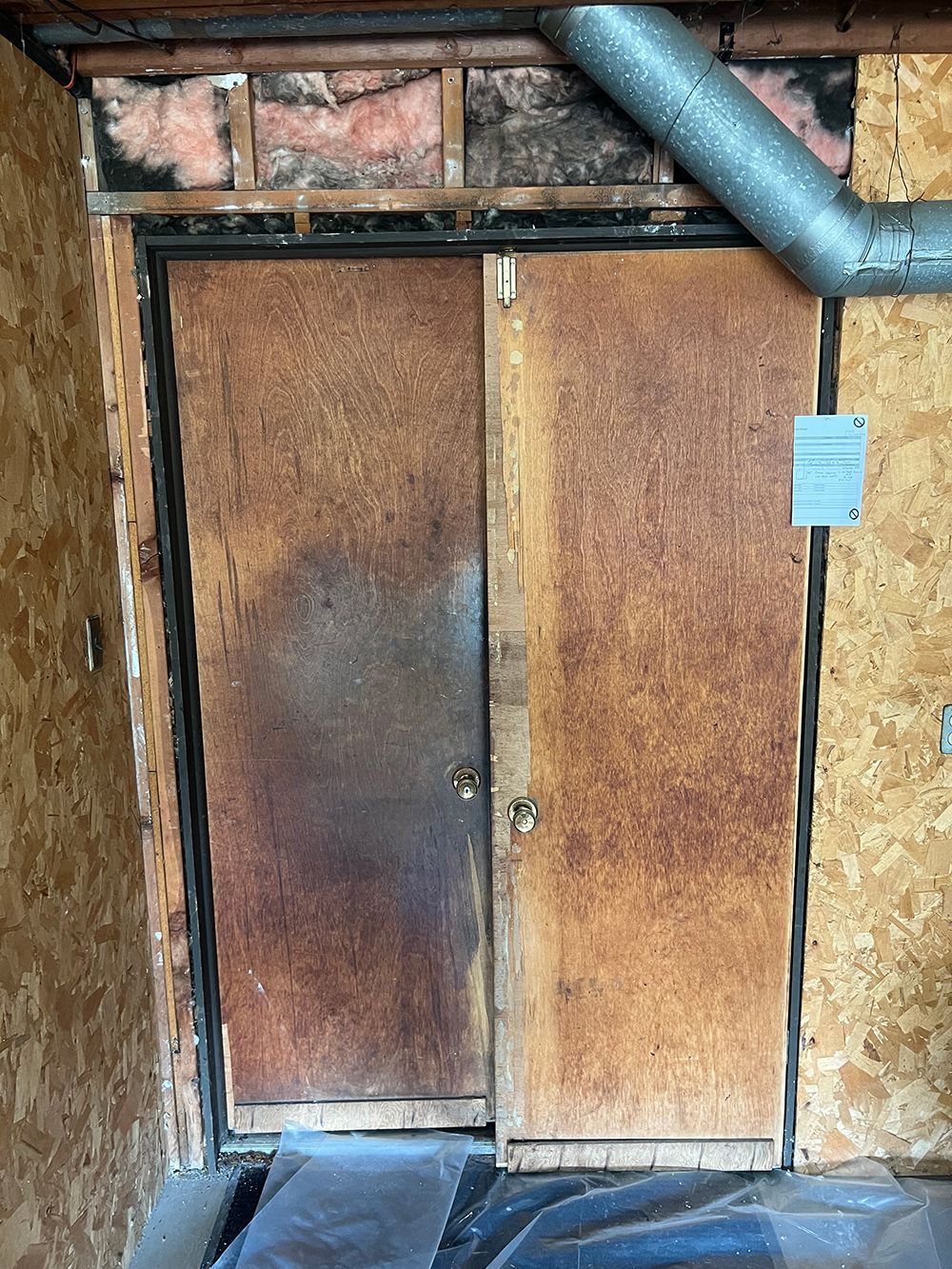Rusty, double-door, sliding door, inside a building, with a gray pipe above.