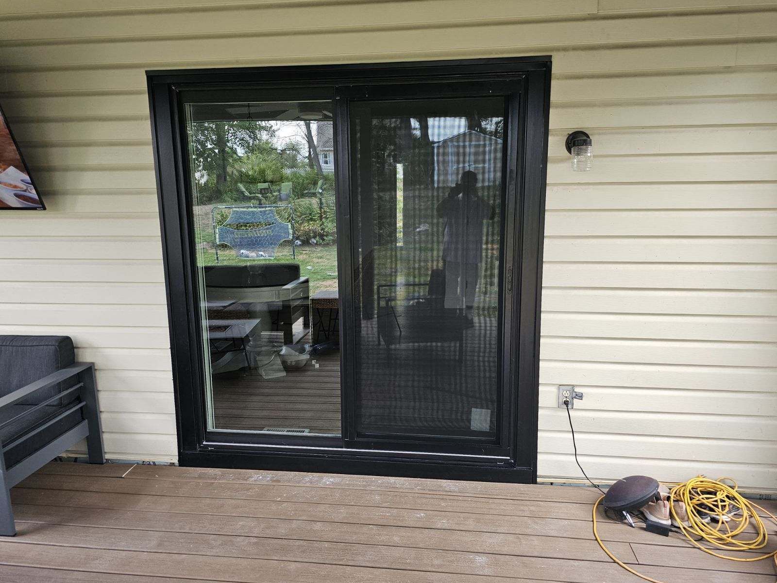 Black sliding glass door with screen on a light beige house exterior.
