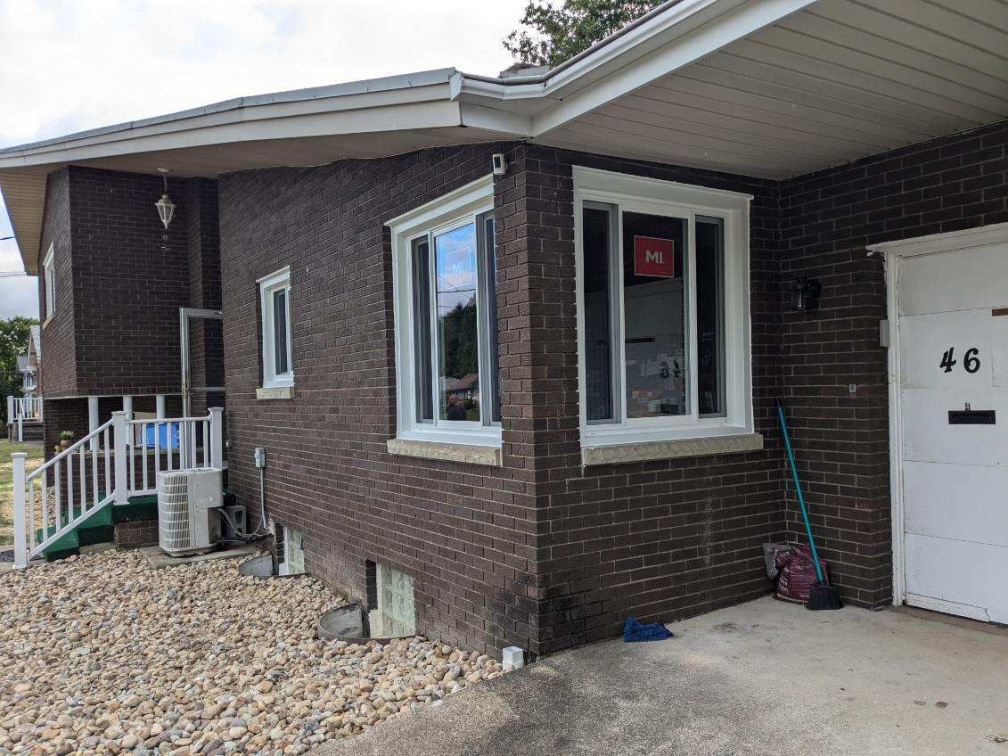 Brown brick building with white windows, a door marked 