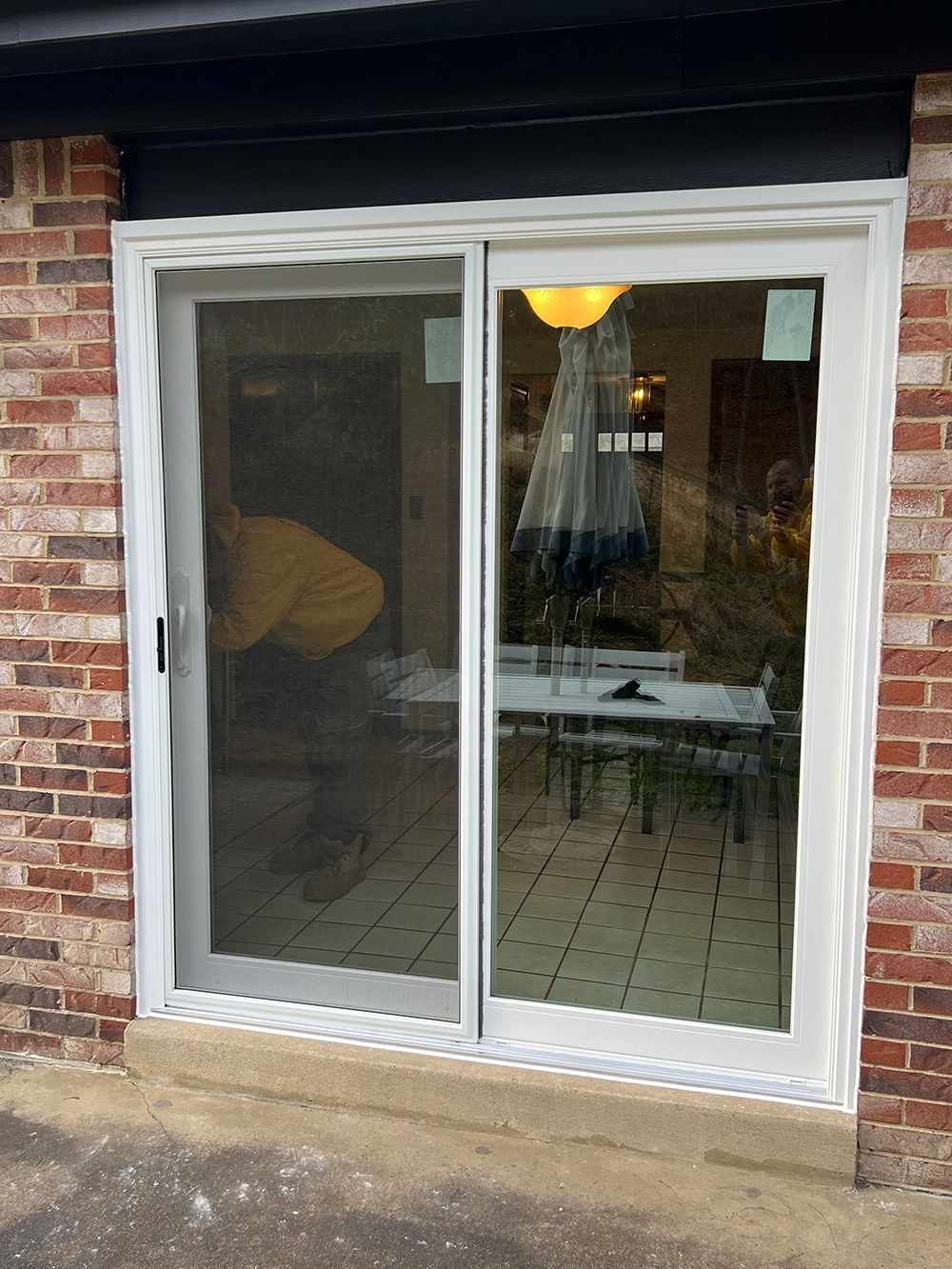 Sliding glass door with screen, set in a brick wall. Exterior shows dining room reflections.