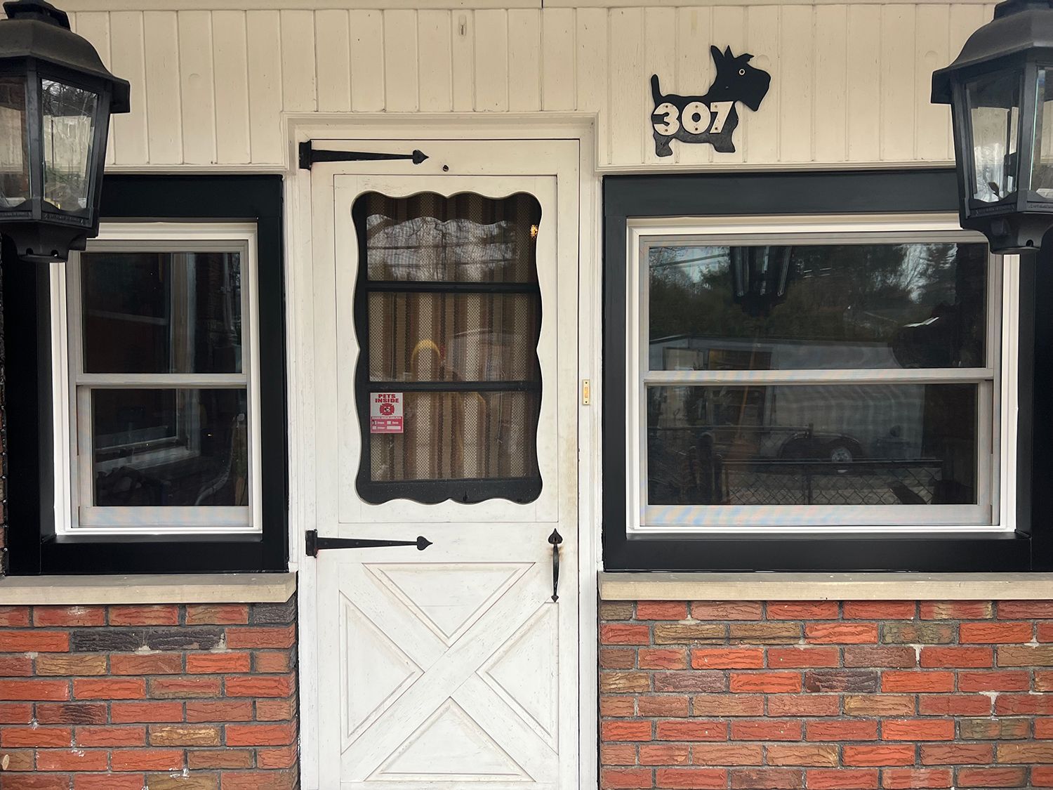 White door with black trim, windows, and brick facade; a dog sign above the door.