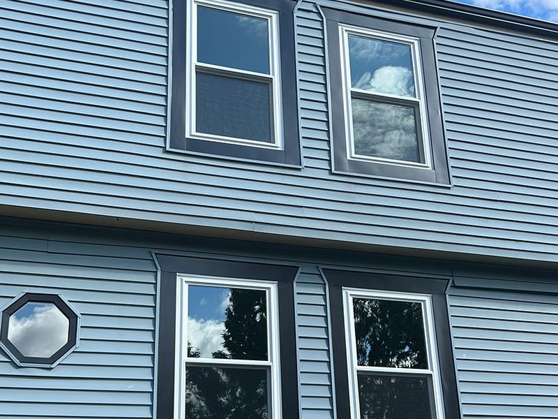 Blue house exterior with four windows, dark trim, and a unique octagonal window.