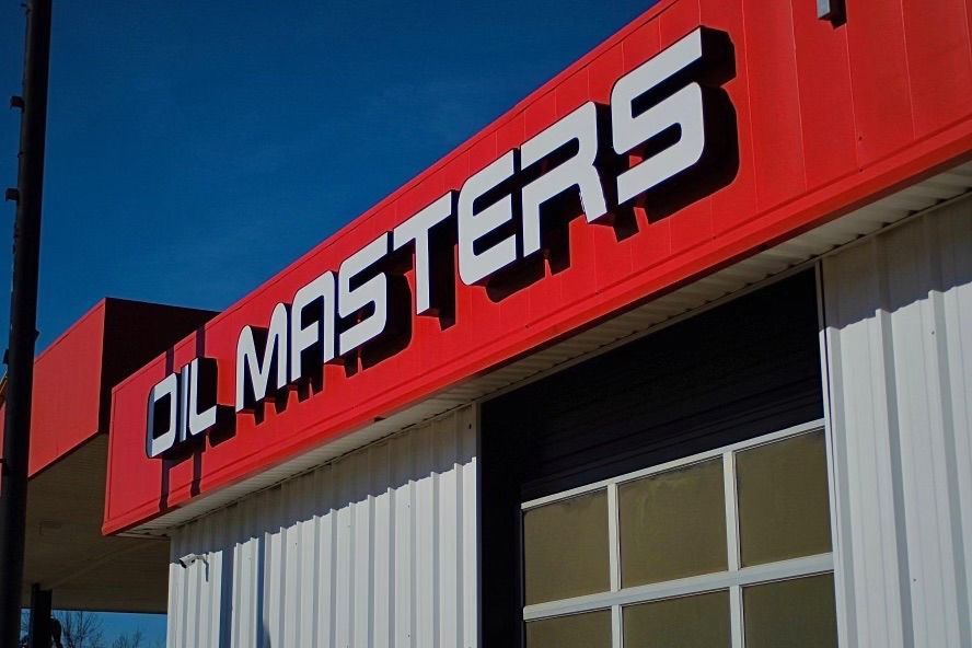 Oil Masters building with red and white sign against a blue sky.