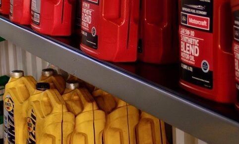 Shelf with rows of red and yellow motor oil bottles.
