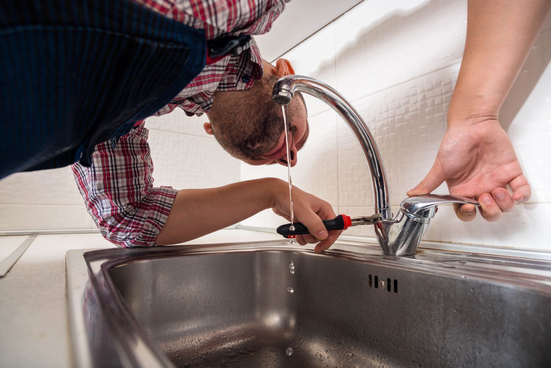 A man is fixing a faucet in a kitchen sink.