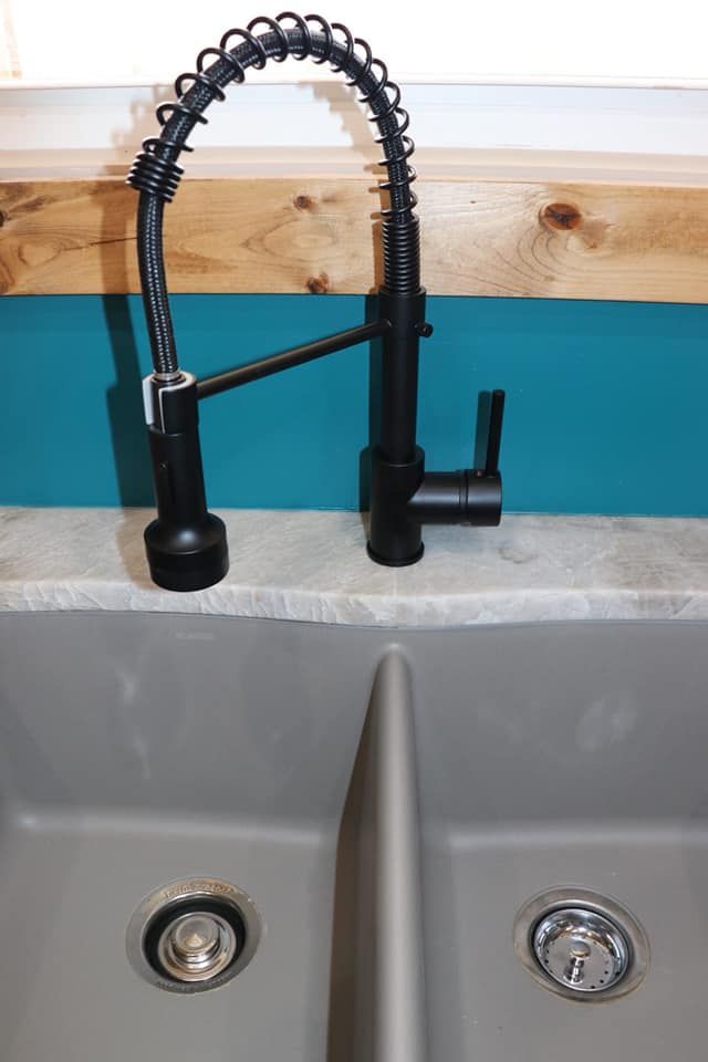 A kitchen sink with a black faucet and two drains
